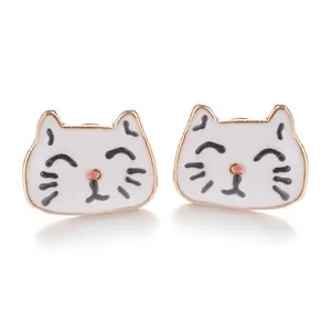 Détail de boucles d'oreilles chat mignon avec émail blanc et bordures en métal doré
