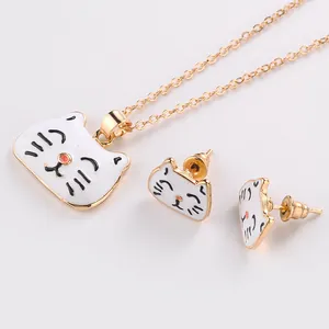 Gros plan d'un collier de chat doré et de boucles d'oreilles en émail blanc assorties