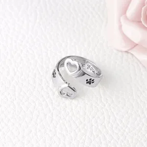 Adjustable silver ring with heart and dog paw prints on white leather background