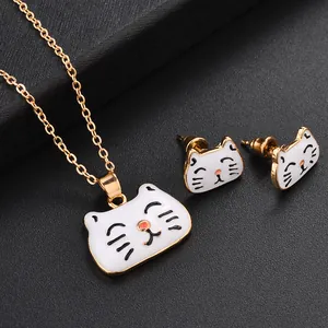 Détail de parure bijoux chat en émail blanc avec collier doré et boucles d'oreilles