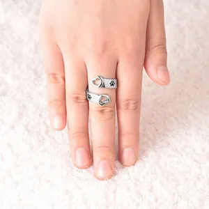 Adjustable silver ring with heart and dog paw prints on soft plush background