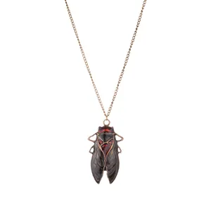 Detail of vintage bronze cicada pendant with dark red enamel on cross chain