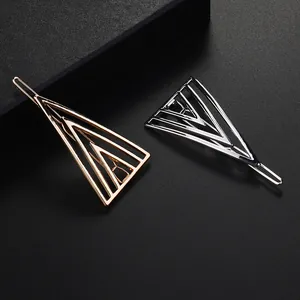 Detailed view of geometric triangle hair clips in polished gold and silver metal finishes