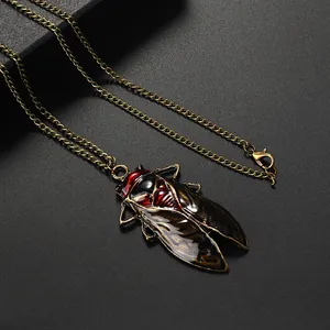 Close-up of vintage bronze cicada necklace with red and black enamel detail and long chain
