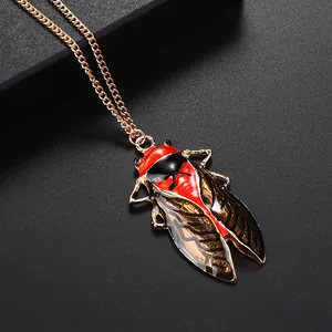 Detail of vintage cicada pendant with red and black enamel finish on a gold chain