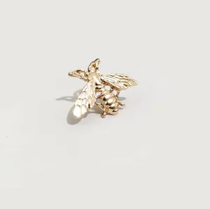Broche de abeja dorada pulida con textura detallada de alas sobre un fondo minimalista