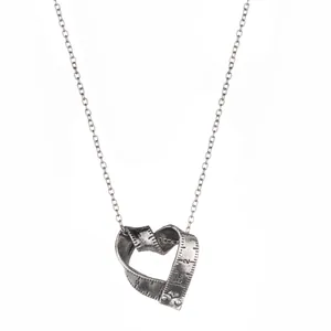 Detail of vintage silver heart necklace with unique ruler scale engraving on pendant