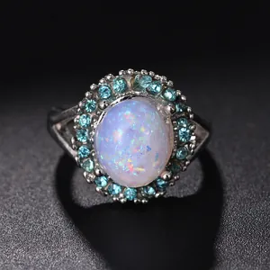 Vista macro de anillo de plata con piedra de ópalo ovalada y halo azulado