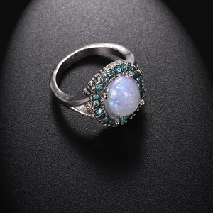 Detalle macro de un anillo de opalo ovalado con halo de pedreria azul en fondo negro