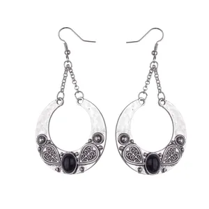 Detail of silver hollow moon earrings featuring retro carvings and black gemstone