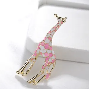 Broche de jirafa moderno en oro con esmalte rosa y blanco sobre fondo blanco texturizado