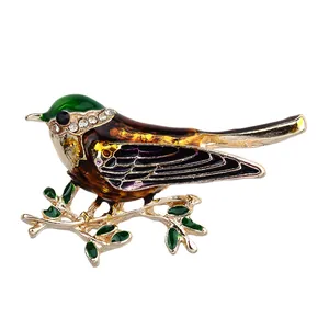 Elegante broche de pájaro con cabeza de esmalte verde y cristales en rama dorada