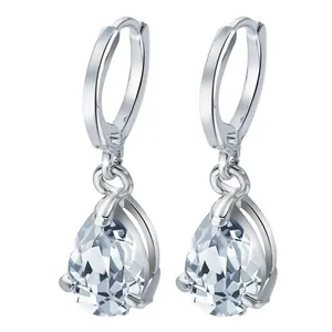 Close-up of silver hoop earrings with teardrop crystal pendants and three-prong setting