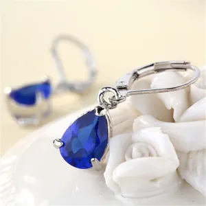 Detailed macro view of pear-cut dark blue crystal drop earrings with silver leverback hooks