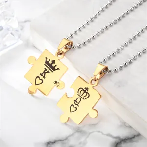 Gros plan de pendentifs puzzle King et Queen dorés avec colliers à billes en acier