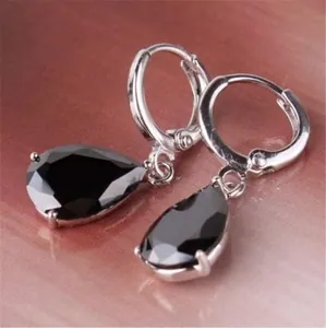 Elegant silver earrings featuring pear-cut black gemstone drops on soft purple background