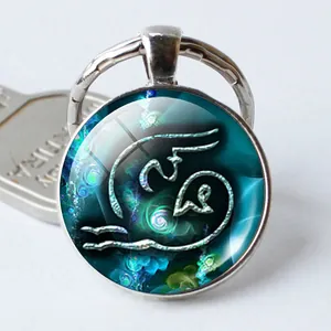 Primer plano de llavero plateado del zodiaco con cabujón de cristal azul y diseño artístico