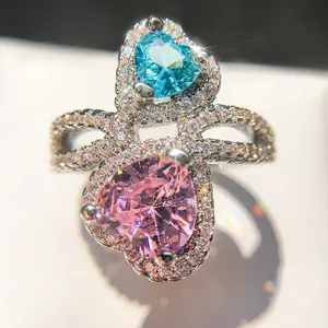 Close-up of heart-shaped blue and pink crystals on silver ring with diamond accents