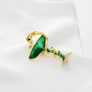 Elegant gold-plated swan and cocktail glass brooch with deep green enamel finish