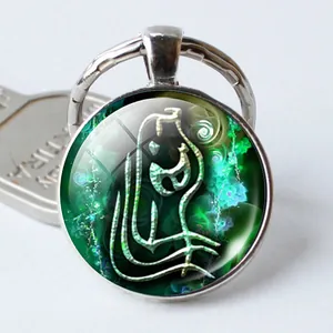 Detalle macro de un llavero plateado del zodiaco con patrón místico verde y vidrio