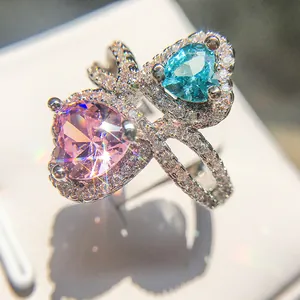 Macro shot of silver ring featuring dual heart-shaped pink and blue crystals and pave zircon