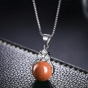 Detalle macro de un collar de plata con un colgante brillante de piedra de arena marrón