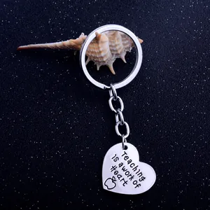 Silver heart keychain engraved with Teaching is a work of heart and apple icon
