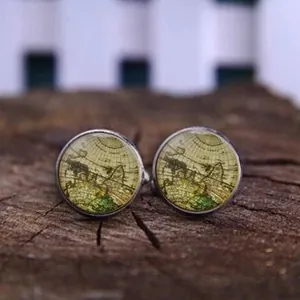 Close-up of vintage world map cufflinks on a rustic wooden background with silver base