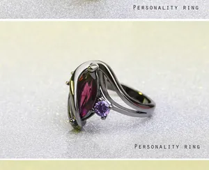 Detail van een golfvormige zwarte metalen ring met een paars marquise-kristal