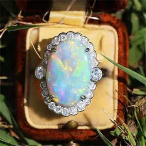 Detalle macro de anillo de opalo ovalado con halo de pedrería en caja de terciopelo