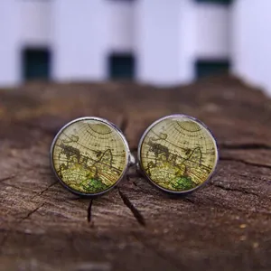 Vintage world map cufflinks with silver base and glass dome on a wooden surface