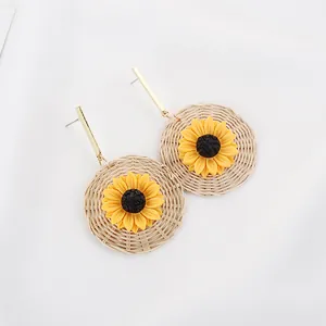 Detailed view of woven rattan earrings with bright yellow sunflowers and gold studs
