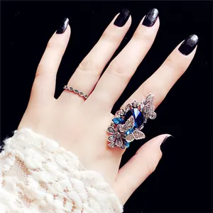 Nahaufnahme der Vintage Schmetterlingsringe mit blauen Kristallen an Model mit schwarzen Nägeln