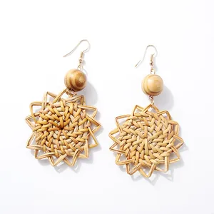 Detailed macro view of bohemian rattan star earrings with natural wooden beads and gold hooks