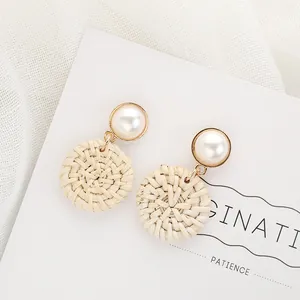 Bohemian woven rattan drop earrings with artificial pearls on elegant white background