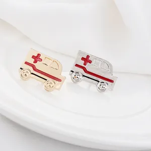 Detalle macro de pines de ambulancia en esmalte dorado y plateado con cruz roja