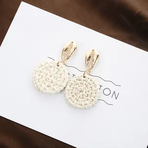 Bohemian shell stud earrings with handwoven round raffia pendants in gold and cream colors