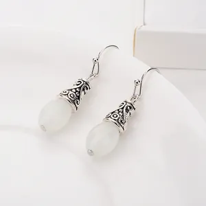Détail de boucles d'oreilles vintage avec pierres blanches et métal en filigrane