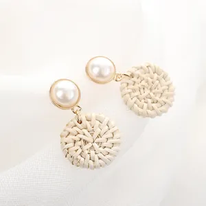 Elegant pearl stud earrings with woven rattan circular pendants and gold-tone metal accents