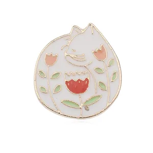 Vista de cerca del broche de esmalte con diseño de gato y flores con bordes dorados
