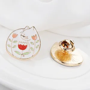 Vista macro del broche de esmalte de gato blanco con flores y cierre de mariposa dorado