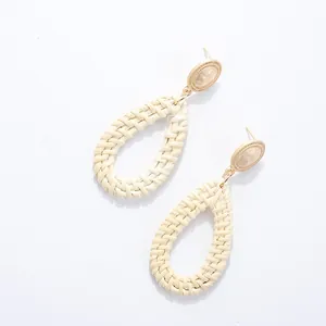 Detail of bohemian teardrop woven rattan earring with golden metal oval stud