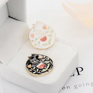 Detalle de pines de esmalte con gatos blancos y negros y flores de tulipanes
