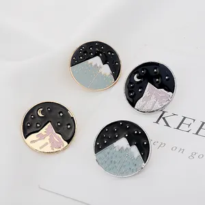 Lot de pins émaillés avec montagnes enneigées et croissant de lune sous ciel étoilé