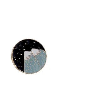 Gros plan détaillé d'un pin's rond en émail représentant une montagne et ciel étoilé
