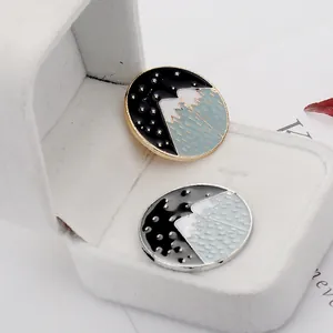 Détail de pin's en émail avec motifs de montagne et ciel étoilé en boîte cadeau