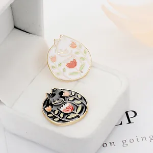 Broches de esmalte de gato y tulipán en blanco y negro sobre un joyero de terciopelo