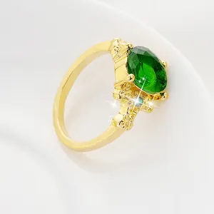Macro d'une bague dorée avec grande pierre verte ovale et détails de texture corail