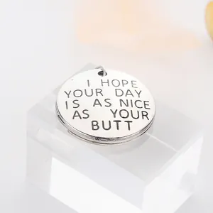 Close-up of silver round keychain with I Hope Your Day Is As Nice As Your Butt engraving