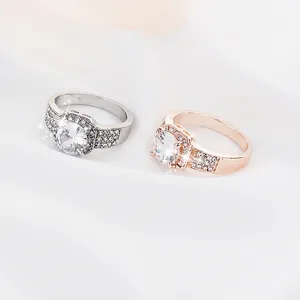 Classic silver and rose gold rings with crystal halo setting on white satin background
